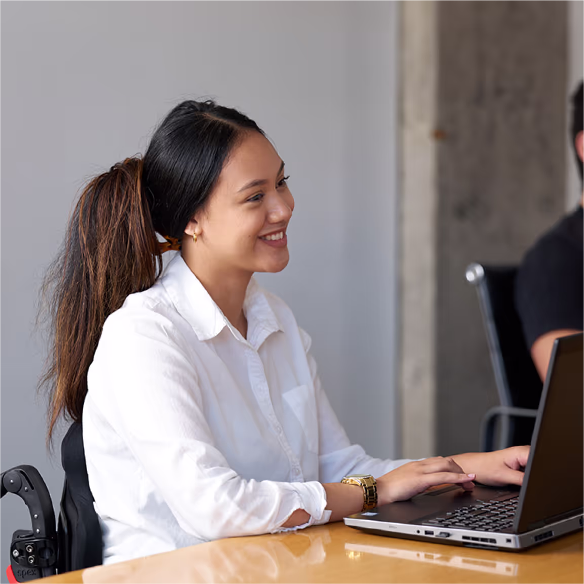 A young woman in a wheelchair using her computer in an office environment. Credit: Medifab.